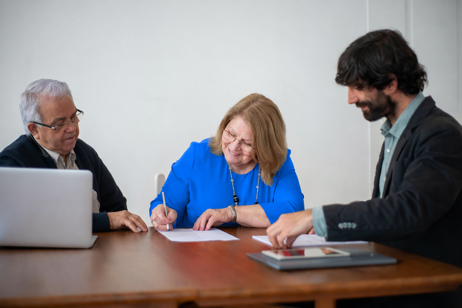 Professionals signing transaction documents in a conference room